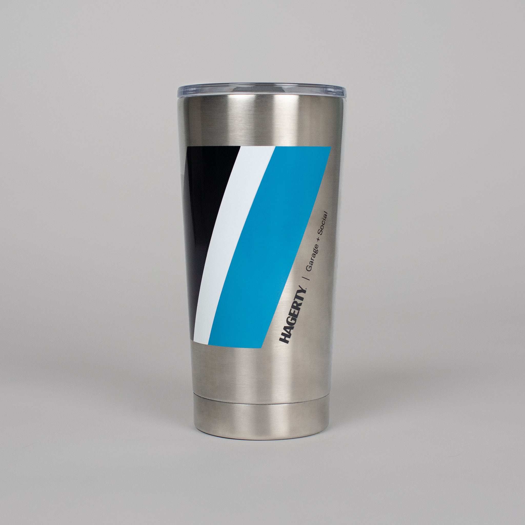 Stainless steel tumbler with the Hagerty and Garage and Social logo alongside the brand's black, white, and blue racing stripe design against an all white background.. Made exclusively for The Shop by Hagerty.